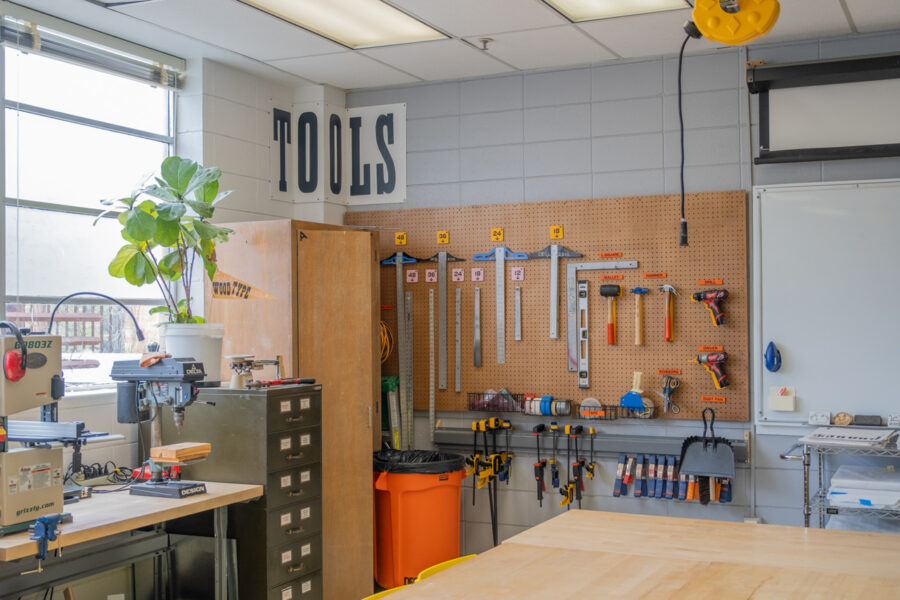 The pegboard with rules and hand tools. A large signs above reads Tools