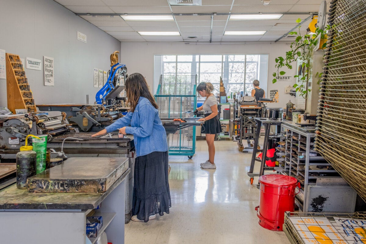 student residency employees work at each of the antique presses in the UT Design Lab