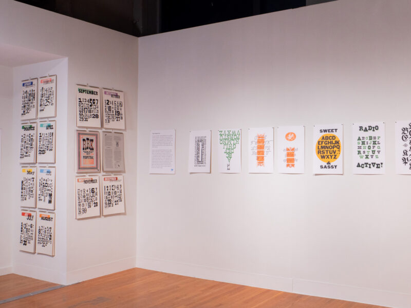 installation of RRK Folio Revisited Specimen prints on wall at the Visual Arts Center at UT Austin, all twelve months of RRK calendar project displayed on the left
