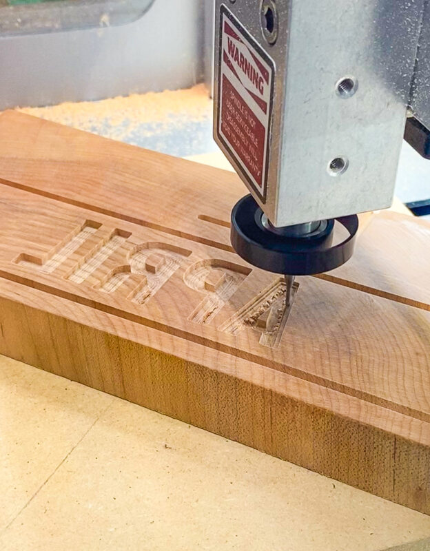 The CNC cutting bit carving the interior of the A in the April block.