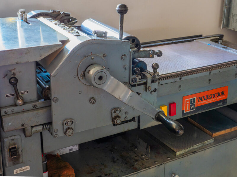A closeup of the SP15 press bed and crank. The polymer base on the bed has a grid for aligning the printing plates.