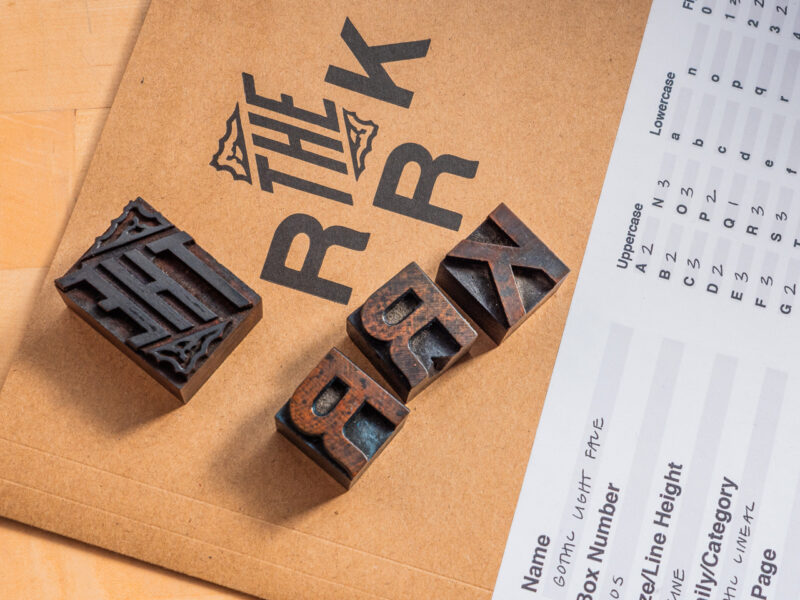 wood type blocks reading The RRK, mirroring the print on the informational folder that is underneath the blocks