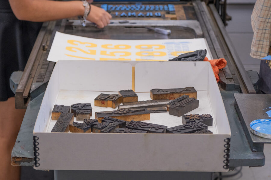 box of decorative ornamental cuts in the RRK collection sitting on the end of a Vandercook press in the UT Design Lab